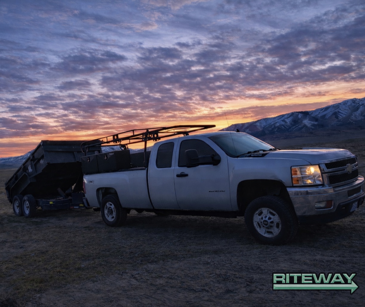 Pickup truck towing Riteway dump trailer at sunset